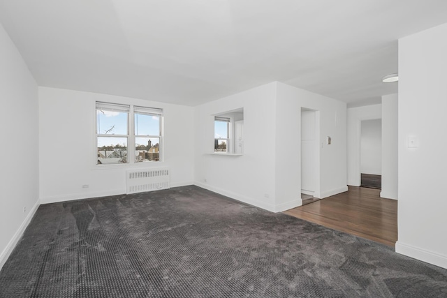 carpeted empty room featuring radiator heating unit