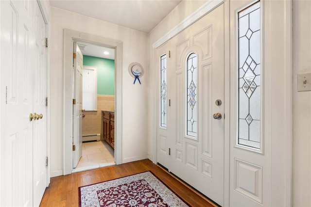 entrance foyer featuring light hardwood / wood-style flooring, a wealth of natural light, and a baseboard heating unit