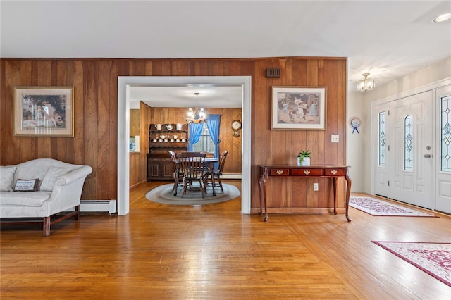 entryway with an inviting chandelier, wood walls, and hardwood / wood-style flooring