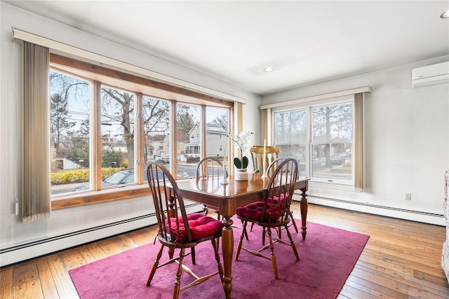 dining room with an AC wall unit, a baseboard heating unit, hardwood / wood-style floors, and a wealth of natural light