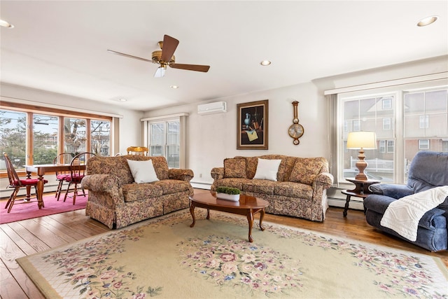 living room with a baseboard radiator, ceiling fan, hardwood / wood-style flooring, and a wall mounted AC