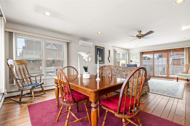 dining area featuring ceiling fan, a wall mounted AC, hardwood / wood-style floors, and a baseboard heating unit