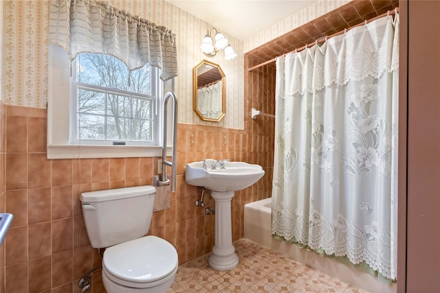 bathroom featuring toilet, tile patterned floors, tile walls, and shower / tub combo