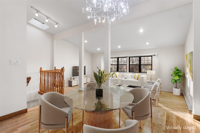 dining room with track lighting, light hardwood / wood-style flooring, and a chandelier