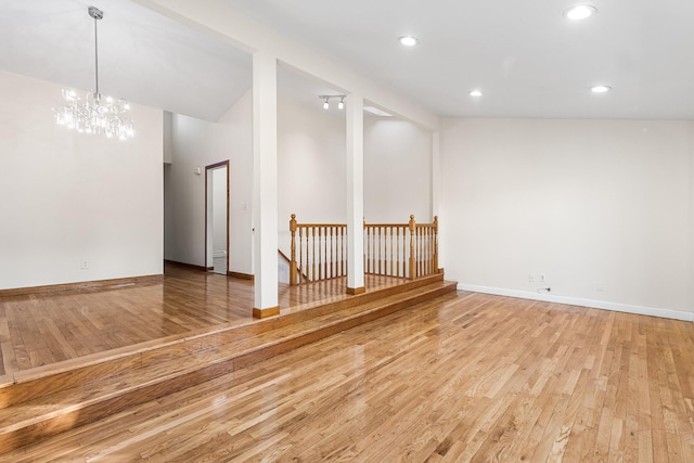 spare room featuring a notable chandelier and light hardwood / wood-style flooring