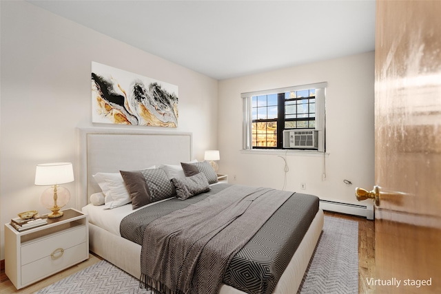 bedroom featuring cooling unit, a baseboard heating unit, and light hardwood / wood-style flooring