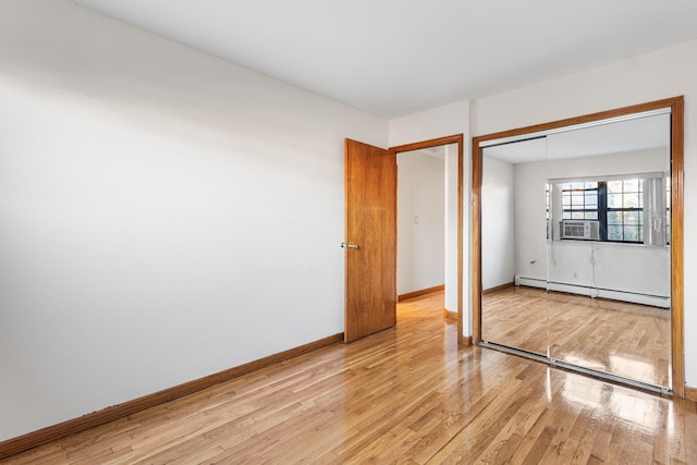 unfurnished bedroom with light hardwood / wood-style floors, baseboard heating, cooling unit, and a closet