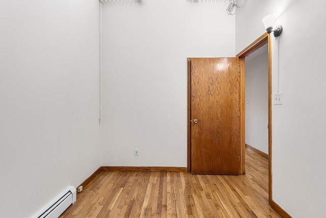 empty room featuring baseboard heating and light hardwood / wood-style flooring