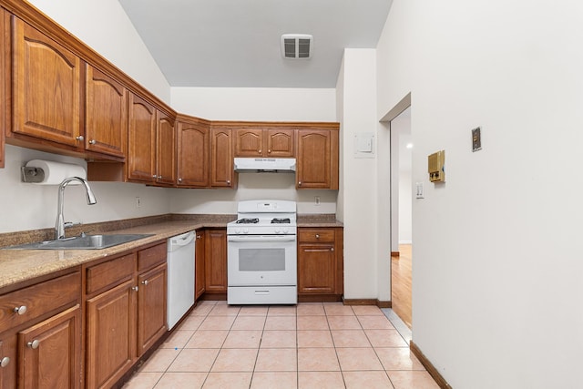 kitchen with white appliances, light stone countertops, light tile patterned floors, and sink