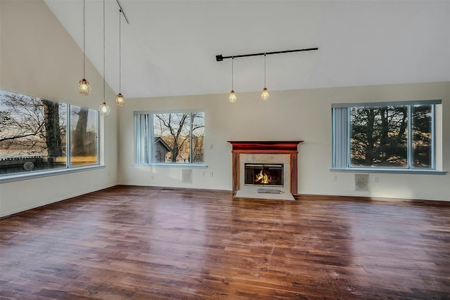 unfurnished living room with rail lighting, vaulted ceiling, and dark hardwood / wood-style floors