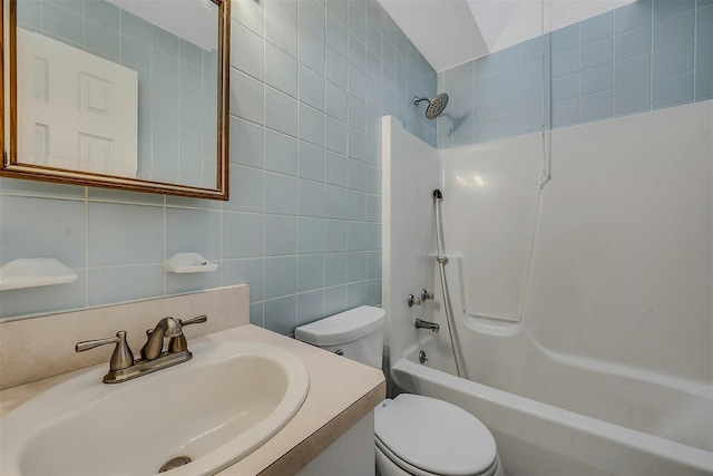 full bathroom featuring washtub / shower combination, toilet, vanity, tile walls, and tasteful backsplash