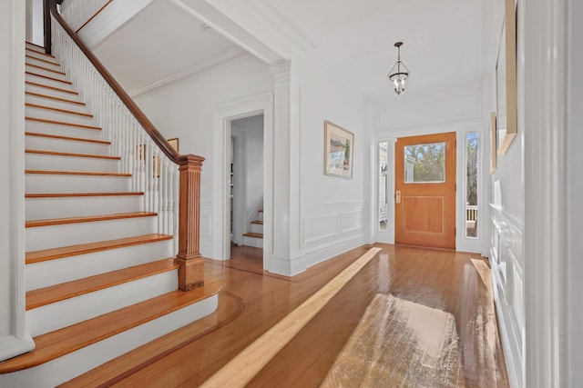 foyer entrance featuring wood-type flooring, a chandelier, and crown molding