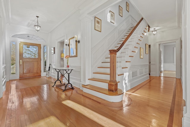 entrance foyer featuring an inviting chandelier, light hardwood / wood-style flooring, and ornamental molding