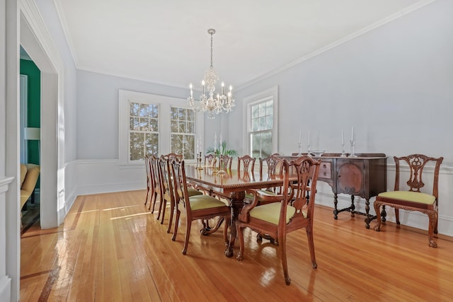 dining area with crown molding, a notable chandelier, and light hardwood / wood-style flooring