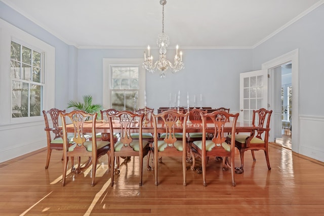 dining room featuring crown molding, a healthy amount of sunlight, hardwood / wood-style floors, and an inviting chandelier