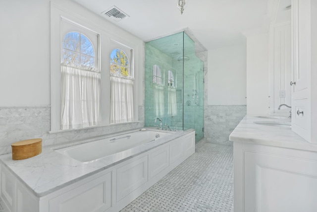 bathroom featuring vanity, tile patterned flooring, independent shower and bath, and tile walls