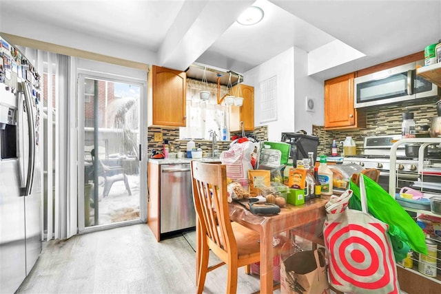 kitchen featuring stainless steel appliances, light hardwood / wood-style floors, and decorative backsplash