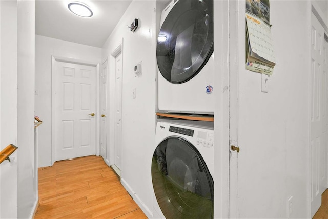 laundry area featuring stacked washer / drying machine and light hardwood / wood-style flooring