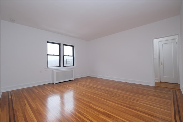 spare room with hardwood / wood-style flooring and radiator heating unit