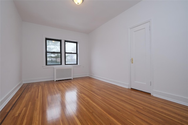 empty room with hardwood / wood-style flooring and radiator heating unit