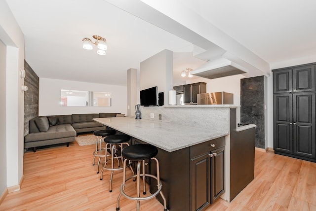 kitchen featuring light hardwood / wood-style floors, stainless steel fridge, a kitchen breakfast bar, and kitchen peninsula