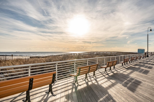 deck at dusk with a water view and a beach view