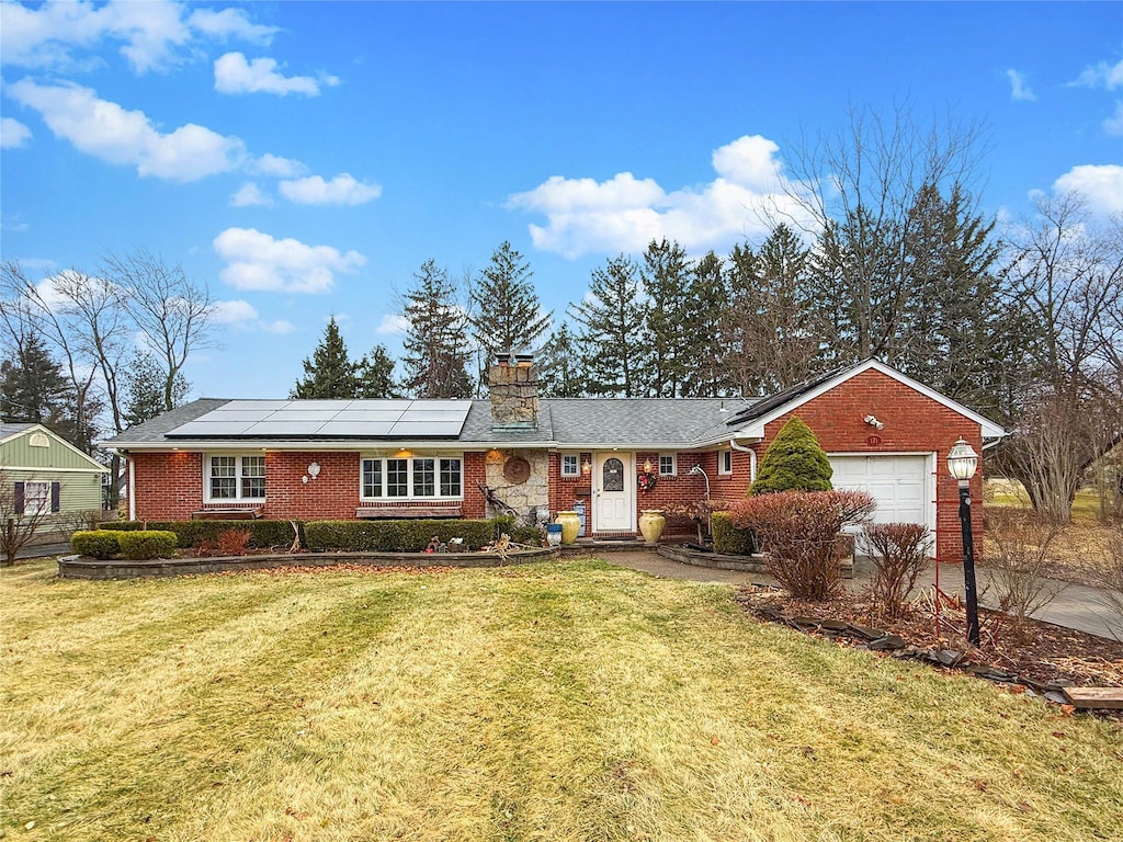 ranch-style home with a garage, solar panels, and a front yard