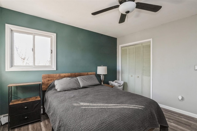 bedroom featuring dark wood-type flooring, a baseboard radiator, ceiling fan, and a closet