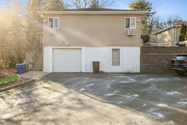 exterior space featuring a garage and an AC wall unit