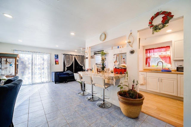 kitchen featuring light tile patterned flooring, a breakfast bar area, white cabinetry, and stainless steel fridge