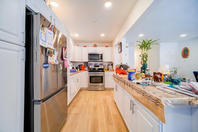 kitchen featuring stainless steel appliances, tasteful backsplash, light wood-type flooring, light stone countertops, and white cabinets