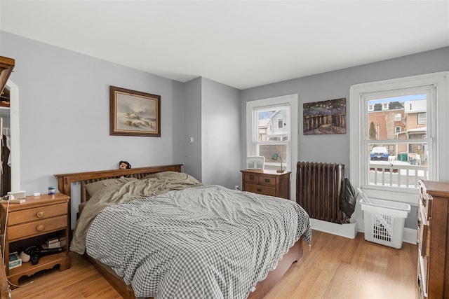 bedroom featuring light hardwood / wood-style floors, radiator, and multiple windows