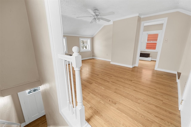 additional living space featuring light wood-type flooring, radiator, ceiling fan, a textured ceiling, and lofted ceiling