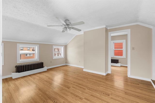 bonus room featuring radiator, a textured ceiling, lofted ceiling, and light hardwood / wood-style flooring