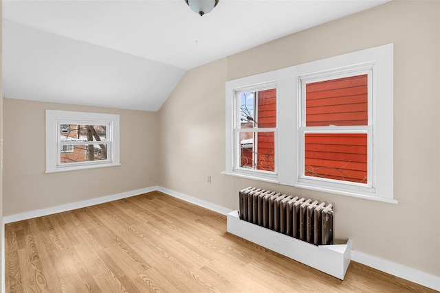 additional living space featuring radiator, lofted ceiling, and light hardwood / wood-style flooring