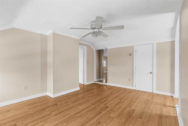 empty room featuring a textured ceiling, ceiling fan, light hardwood / wood-style flooring, and lofted ceiling