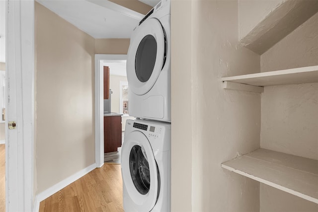 washroom featuring stacked washer / drying machine and light hardwood / wood-style flooring