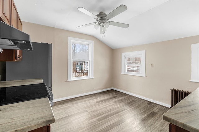 kitchen featuring electric range, vaulted ceiling, light wood-type flooring, radiator, and ceiling fan