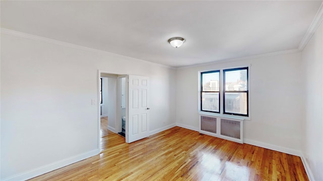 spare room featuring radiator heating unit, light hardwood / wood-style flooring, and ornamental molding