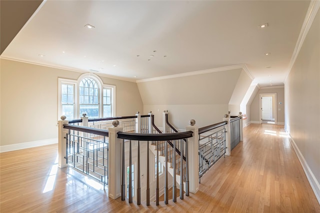 hall featuring light wood-type flooring, vaulted ceiling, and crown molding