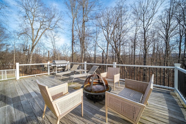 wooden terrace with a fire pit and area for grilling