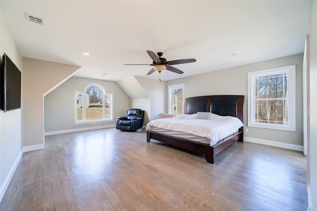 bedroom with ceiling fan, multiple windows, and hardwood / wood-style floors