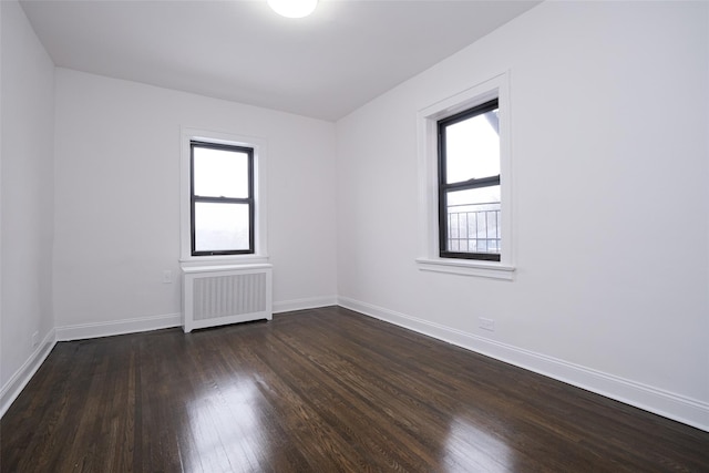 spare room with radiator heating unit, dark hardwood / wood-style flooring, and a wealth of natural light