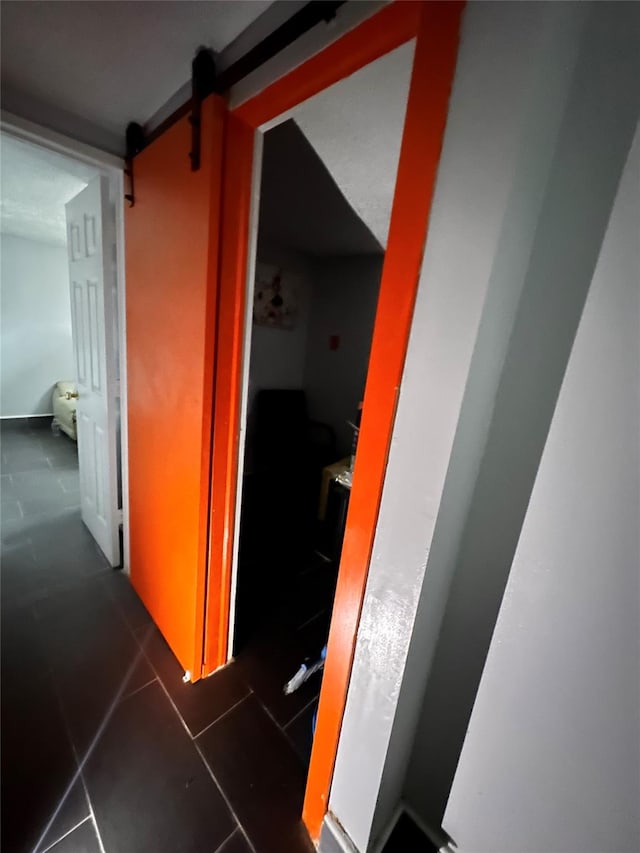 hallway with dark tile patterned floors and a barn door