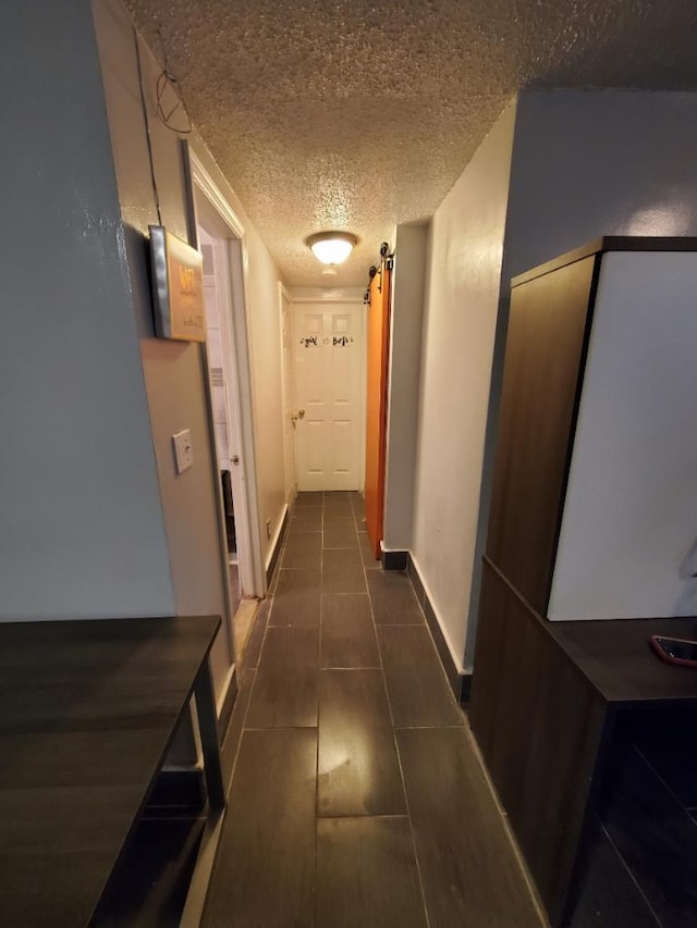 corridor with a textured ceiling and a barn door