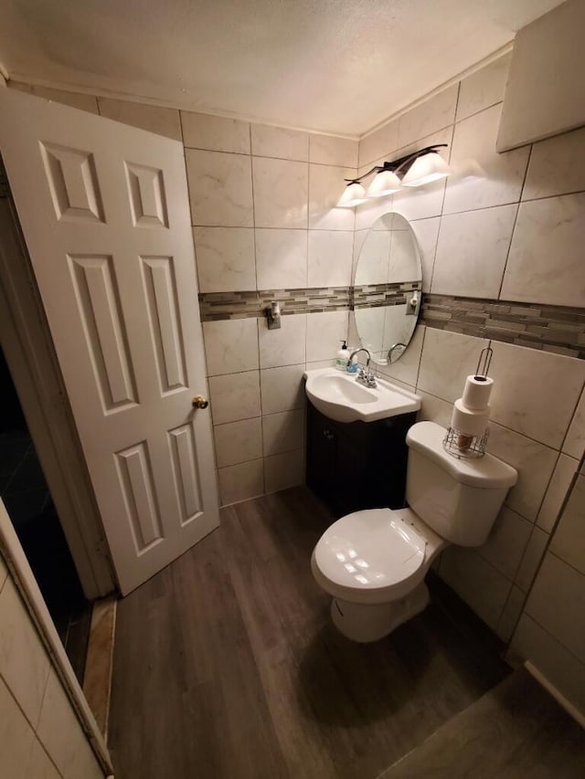 bathroom featuring toilet, vanity, tile walls, and hardwood / wood-style floors