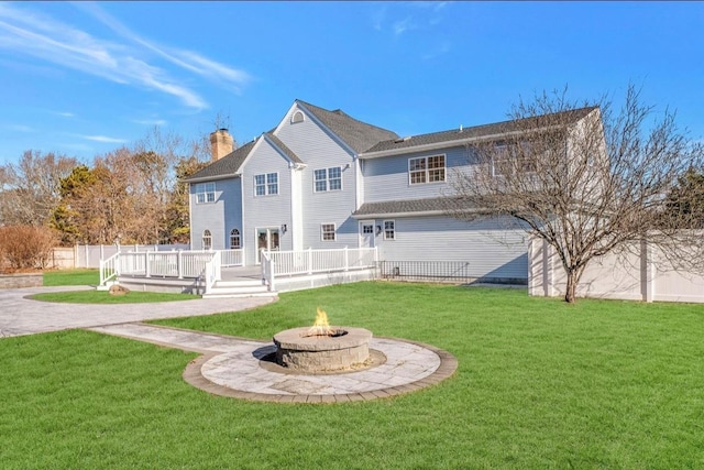 rear view of property with a yard, a fire pit, and a wooden deck