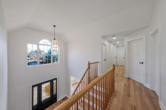 hallway featuring lofted ceiling, an inviting chandelier, and light hardwood / wood-style floors