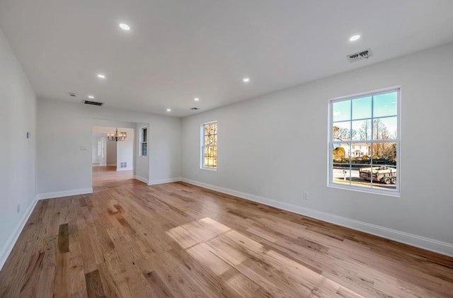 unfurnished room featuring an inviting chandelier and light hardwood / wood-style flooring