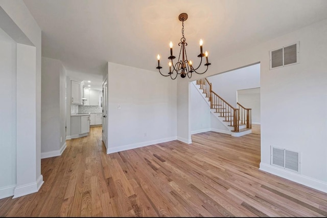 unfurnished dining area with light hardwood / wood-style floors and a notable chandelier